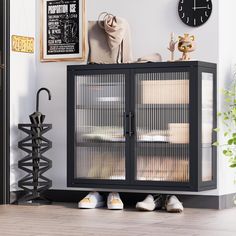 a black cabinet with two doors and some baskets on the bottom, in front of a clock