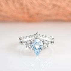 a ring with an aqua blue topazte surrounded by white diamonds on a table