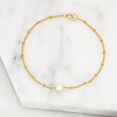 LILY & ROO's delicate handmade single pearl bracelet in gold. This classic yet contemporary single pearl bracelet is made from 14ct gold filled satellite chain and a beautiful single freshwater seed pearl. A stunning jewellery gift for her that goes with any outfit. All single pearl bracelets on satellite chain come in a luxury LILY & ROO box. Gold Filled means a layer of pure gold pressure-bonded to the core metal. Gold filled items are 5 to 10 times thicker than gold plating. Give your jewellery a little TLC to keep your jewellery shining bright. Your stunning pearl bracelet will be sent to you in a complimentary Lily & Roo gift box with ribbon tied in a beautiful bow. Dainty Gold Chain Bracelet With Pearl Charm, Dainty Gold-plated Pearl Chain Bracelet, Dainty Gold Plated Bracelets With Pearl Charm, Dainty Gold-plated Bracelets With Pearl Charm, Dainty Gold Bracelet With Pearl Chain, Minimalist 14k Gold-filled Pearl Bracelet, Delicate Gold Chain Bracelet With Pearl Charm, Yellow Gold Chain Bracelet With Pearl Charm, Dainty Gold Plated Pearl Chain Bracelet