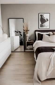 a bed sitting next to a white dresser under a purple and black blanket on top of it