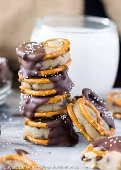 a stack of cookies with chocolate and pretzel toppings next to a glass of milk