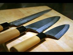 three knives are sitting on a cutting board