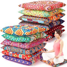 a woman sitting on the ground next to many different colored pillows and pillowcases