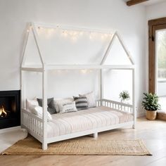 a white bed sitting in a bedroom next to a fire place with lights on it