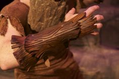 a close up of a person holding something in their hand with wood carvings on it