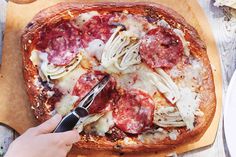 someone is cutting into a pizza with meat and cheese