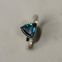 It is a real London blue topaz  ring. The main stone is 8 mm*8mm triangular.The basic metal is sterling silver and plated with rhodium.To change the metal to a solid gold (white/rose) or platinum is also available, please ask for a quotation if you want.You can also go to my shop Home for more elegant rings: https://www.etsy.com/shop/godjewelry?ref=hdr_shop_menuTopaz is November birthstone.More topaz rings:https://www.etsy.com/shop/godjewelry?ref=hdr_shop_menu&section_id=20715039Customizatio Trillion Cut Topaz Jewelry For Anniversary, Formal Trillion Cut Topaz Ring In Fine Jewelry Style, Trillion Cut Sterling Silver Ring With Gemstone, Formal Trillion Cut Topaz Fine Jewelry Ring, Elegant Trillion Cut Topaz Promise Ring, Silver Trillion Cut Sapphire Ring, Fine Jewelry Topaz Ring With Trillion Cut Gemstone, Fine Jewelry Topaz Ring With Trillion Cut, Fine Jewelry Trillion Cut Topaz Ring