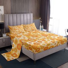 a bed with yellow and orange bedspread in a bedroom next to a window