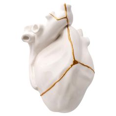 a white ceramic heart with gold lines on it's side and the inside of its body