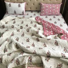 an unmade bed with pink and white sheets