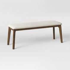 a wooden bench with a white upholstered seat and back rest on an off - white background