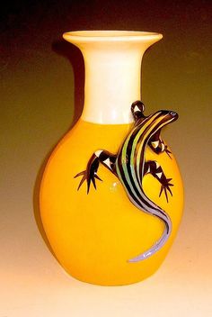 a yellow vase with a lizard painted on it