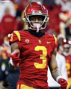 a football player wearing a red and yellow uniform with his tongue sticking out in the air