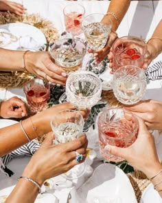 many people are holding wine glasses together