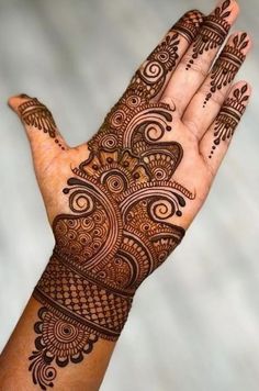 a hand with henna tattoos on it, and an intricate design in the middle