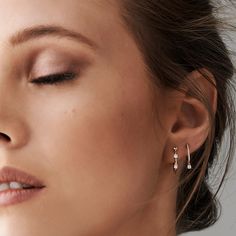 a woman with her eyes closed wearing diamond earring and white topaze earrings