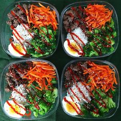 four plastic containers filled with food on top of a green tablecloth covered flooring