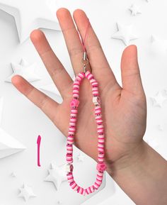 a hand is holding a pink and white beaded necklace on it's string