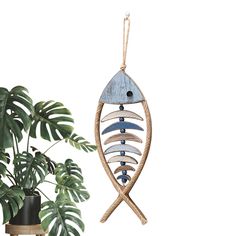 a wooden fish ornament hanging from a rope next to a potted plant