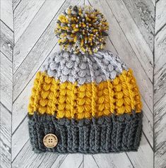 a multicolored knitted beanie with a button on the side and a pom - pom at the top