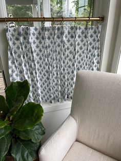 a white chair sitting in front of a window next to a green potted plant