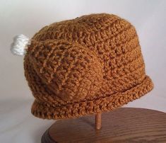 a brown crocheted hat on top of a wooden stand