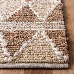 an area rug with white and brown colors on top of a wooden floor next to a wood floor