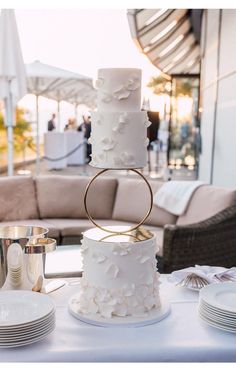 a white wedding cake sitting on top of a table next to plates and silverware