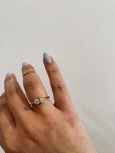 a woman's hand with a ring on it and two diamonds in the middle