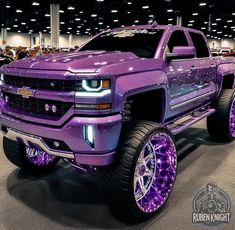 a purple truck with chrome rims parked in a showroom