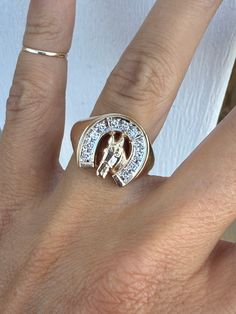 a woman's hand with a ring on it that has a horse in the middle