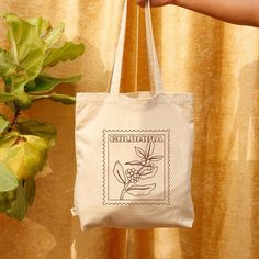 Bring a touch of Colombia to your daily style with this beautiful tote bag featuring an outlined illustration of a coffee plant! Placed in the center, its clean and minimalistic design makes this tote ideal for casual outings, market trips, or your daily errands. Key Features: - 100% certified organic cotton twill - Fabric weight: 272 g/m² (8 oz/yd²) - Dimensions: 40.6 cm × 35.6 cm × 12.7 cm (16" x 14 ½" x 5") - Weight limit: 13.6 kg (30 lbs) - 2.5 cm (1") wide straps, 62.2 cm (24.5") long - Exc Eco-friendly Customizable Tote Shoulder Bag, Green Tote Bag With Eco-friendly Ink, Eco-friendly Recyclable Tote Shoulder Bag, Cotton Tote Bag With Plant Print, Eco-friendly Tote Bag With Plant Print, Colombian Culture, Coffee Plant, Plant Design, Wide Straps