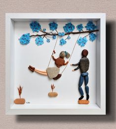 a man and woman are sitting on a swing with blue flowers hanging from the branches