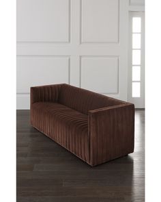 a brown couch sitting on top of a hard wood floor next to a white wall