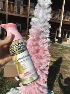 someone is spray painting a pink christmas tree with white tinsel and pink frosting