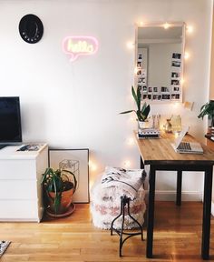 a desk with a laptop on it in front of a neon sign that reads hello