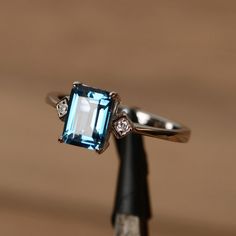 It is London blue topaz ring, the emerald cut topaz is crafted in sterling silver with white gold plated. The side stone is cubic zirconia. It is made Emerald Cut Topaz Ring In 14k White Gold, Sterling Silver Topaz Baguette Cut Ring Gift, White Gold Emerald Cut Topaz Ring, Baguette Cut Sterling Silver Topaz Ring For Gift, Sapphire Topaz Emerald Cut Promise Ring, Emerald-cut Topaz Ring In 14k White Gold, Emerald Cut Blue Topaz Ring In White Gold, Emerald Cut Topaz Ring Gift, Classic 14k White Gold Emerald-cut Topaz Ring