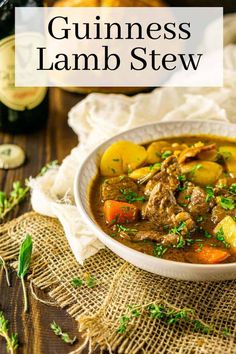 a white bowl filled with meat and vegetables next to a bottle of guinness lamb stew