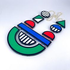 Colour block necklace is a large,fun, bold statement piece. This colourful accessory would look great with any outfit.  The necklace is delicately made with cut out green, blue, white and red acrylic, inserted in a bold black outline and Layered on a clear background. These are linked together using jump rings and has a silver plated curb chain. This has no back clasp, instead you pull over your head.  If you have any questions drop us a line!💌 We are more than happy to help! 😁 To clean your necklace you can simply wipe with a glasses cloth or soft cloth to remove finger marks. Acrylic is a fragile material so please store in a jewellery box to prevent damage.  As ever for safety please keep away from small children. Perspex Jewelry, Plastic Jewellery, Flamingo Necklace, Bright Jewelry, Polymer Inspiration, Laser Cut Jewelry, Acrylic Necklaces, Clear Background, Colorful Accessories