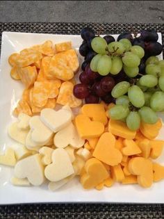 grapes and cheese are arranged on a white platter