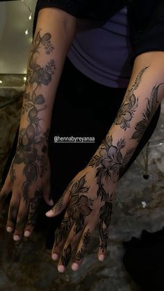 a woman's arm with flowers on it and her hands covered in black ink