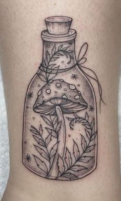 a woman's leg with a tattoo on it that has a bottle filled with mushrooms and leaves