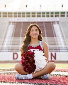 a cheerleader sitting on the ground with her pom - poms