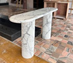 a white marble bench sitting on top of a wooden floor