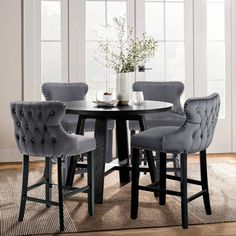 a dining room table with grey chairs and a rug on the floor in front of it