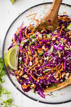 a bowl filled with coleslaw, carrots and lime wedged into it