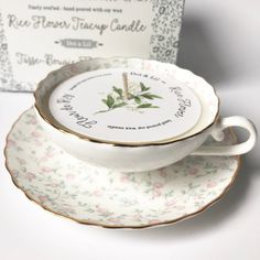 an empty tea cup and saucer sitting next to a boxed card on a table