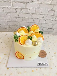 a white cake with oranges and meringue on top sitting on a table