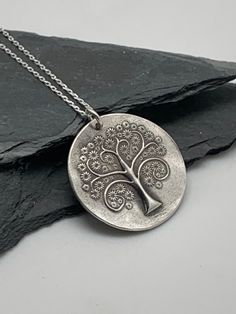 This unique tree of life handmade embossed round pendant has been entirely handmade using .999 fine silver. It has been cut from fine silver precious metal clay, textured, fired and oxidized. The pendant hangs from a sterling silver diamond cut cable chain. This fine silver pendant features an embossed tree of life on one side of the pendant and is reversible to a wood grain embossed pattern on the reverse side. Pendant size: approximately 1 x 1 inches Chain length: adjustable at 16 and 18 inche Silver Clay Jewelry Ideas, Embossed Pattern, Metal Clay Jewelry, Pendant Necklace Silver, Precious Metal Clay, Unique Trees, Silver Tree, Tree Pendant, Metal Clay