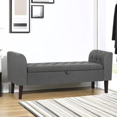 a gray bench sitting on top of a hard wood floor next to a white wall